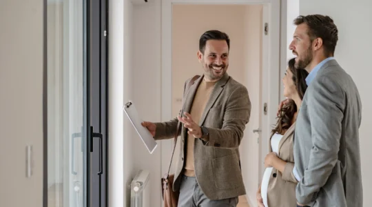 Vermieter mit Mietern bei der Wohnungsvorabnahme