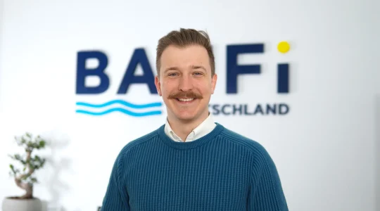 Ricardo Tunnissen, Mitgeschäftsführer von Baufi Deutschland, vor dem Firmenlogo