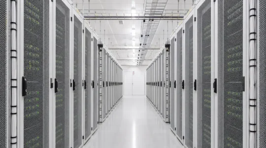 Heller Gang zwischen zwei Reihen Serverschränken in einem modernen Rechenzentrum